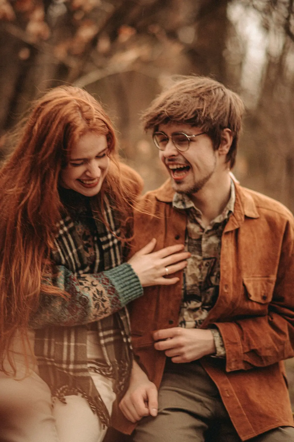A couple laughing together among autumn trees